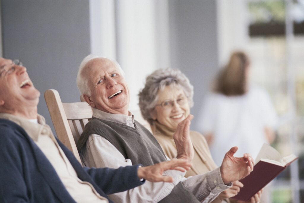 Three elderly people sitting next to each other, laughing